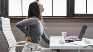 Imagen de una persona con mala postura en su lugar de trabajo, ignorando los principios de ergonomía